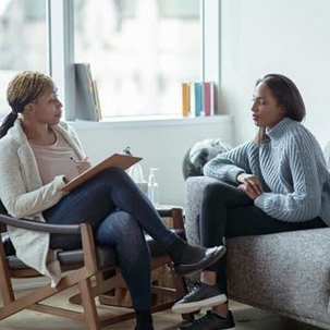 Woman sits on couch as she talks to her therapist