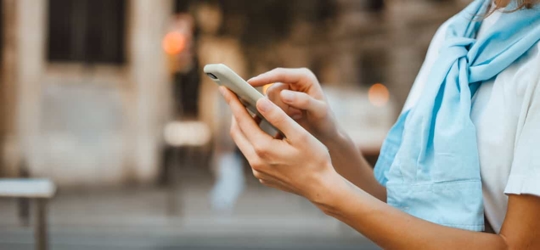 Close up of a young person using a smartphone on the street