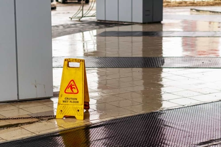 Yellow wet floor triangle sign stands on a wet floor