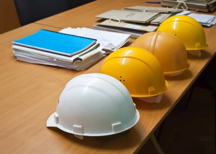 Hard hats sit on a table with documents