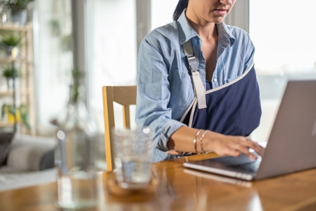 Woman with broken arm looks up information on her laptop