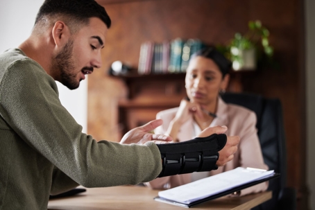 Man with broken arm discusses his injury with a personal injury attorney in her office