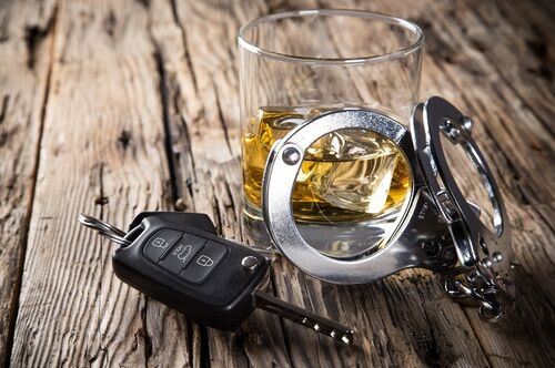 hand cuffs up against a alcoholic drink and keys