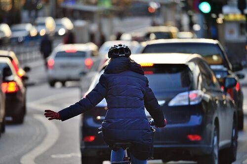 Rear of bicyclist with hand out on the road with other drivers