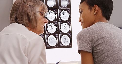 Older female doctor looking at MRI of brain with female patient